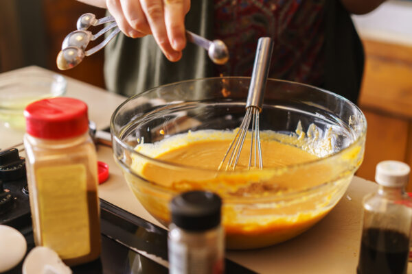 adding spices with measuring spoon to pumpkin pie 2023 11 27 04 50 19 utc